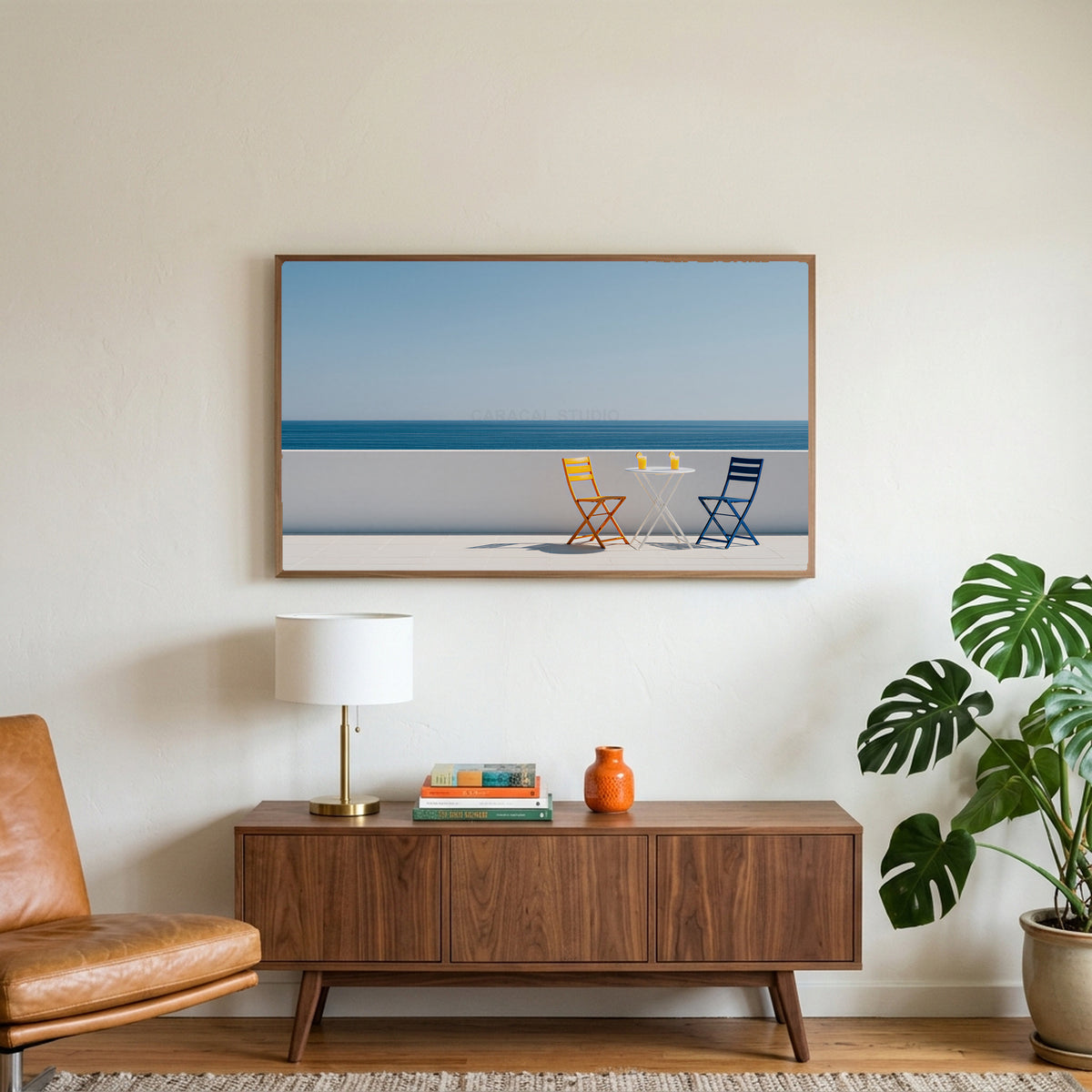 Ocean view terrace art on a TV above a walnut credenza with a brass lamp and a monstera plant