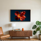 Red lily on navy art on a TV above a walnut credenza with a brass lamp and a monstera plant
