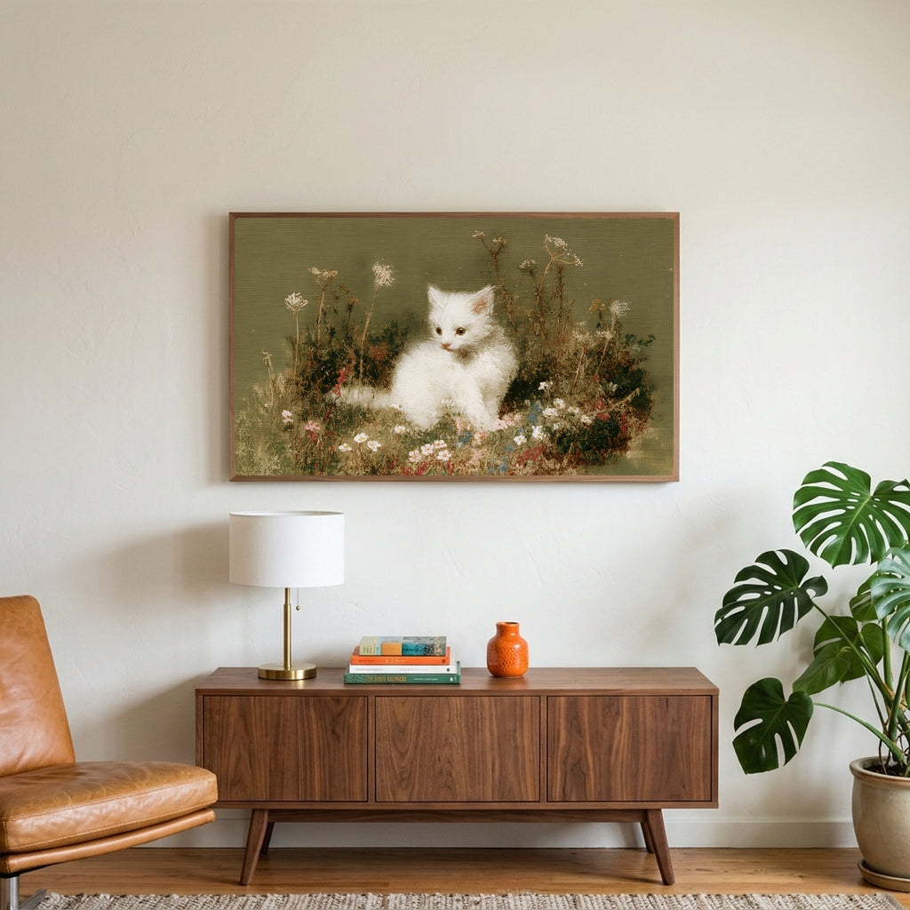 White kitten art on a TV above a walnut credenza with a brass lamp and a monstera plant