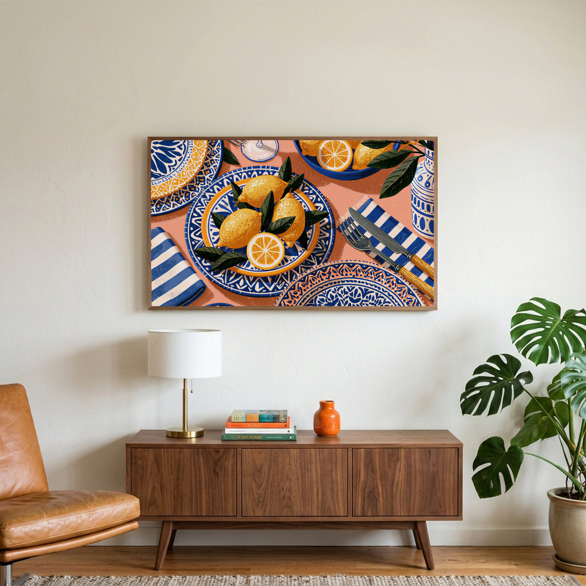 Mediterranean lemons art on a TV above a walnut credenza with a brass lamp and a monstera plant