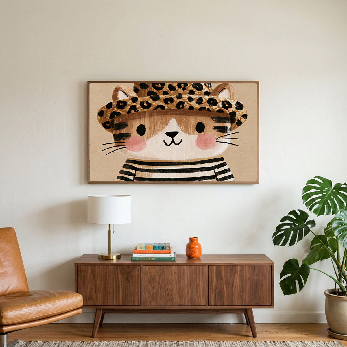 Kitten in a leopard hat art on a TV above a walnut credenza with a brass lamp and a monstera plant