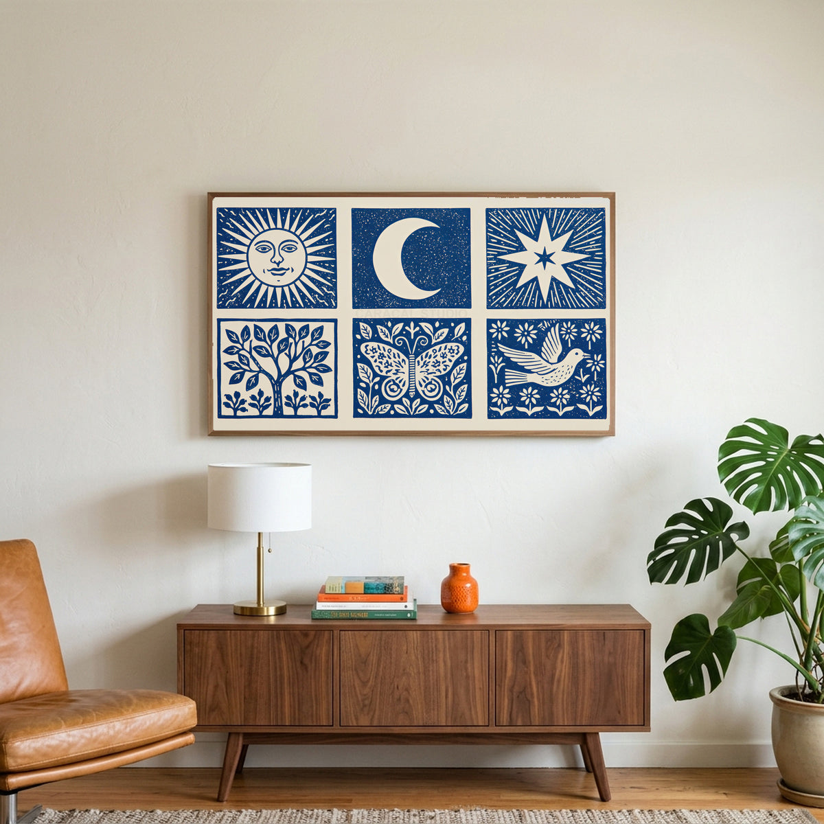 Celestial folk art on a TV above a walnut credenza with a brass lamp and a monstera plant