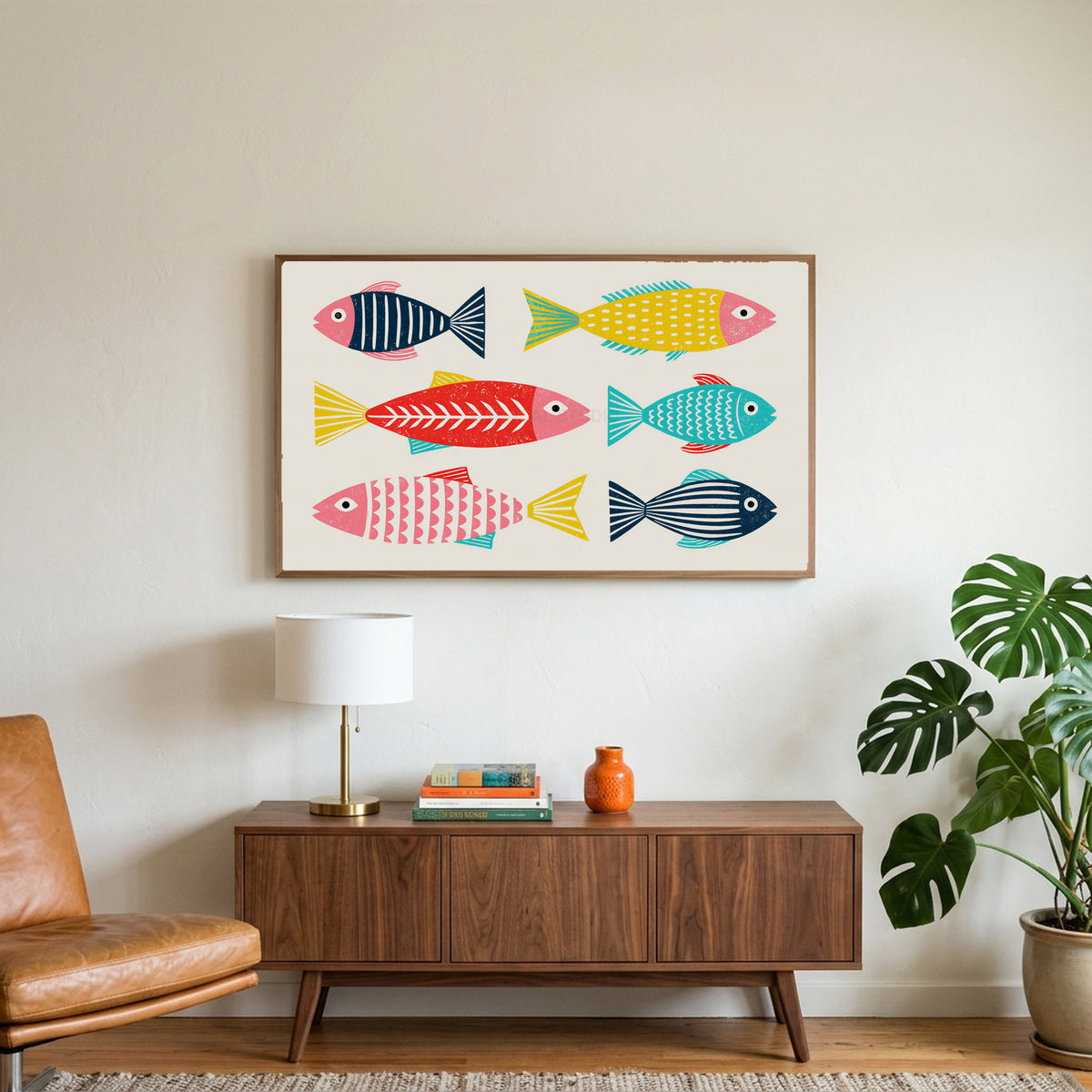 Linocut fish art on a TV above a walnut credenza with a brass lamp and a monstera plant
