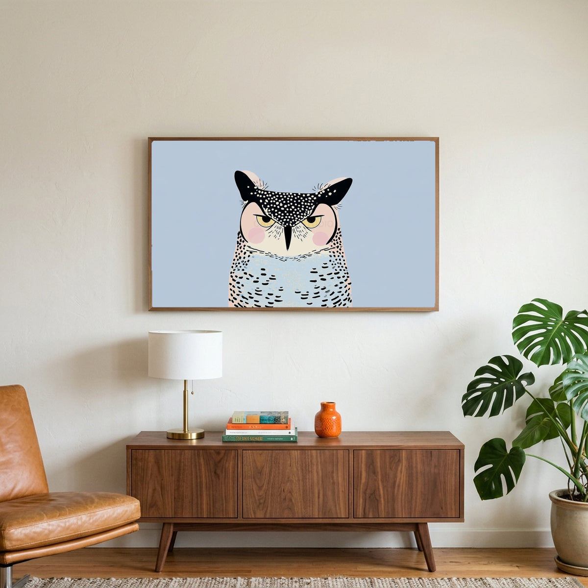 Grumpy owl art on a TV above a walnut credenza with a brass lamp and a monstera plant