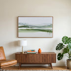 Misty wetland art on a TV above a walnut credenza with a brass lamp and a monstera plant