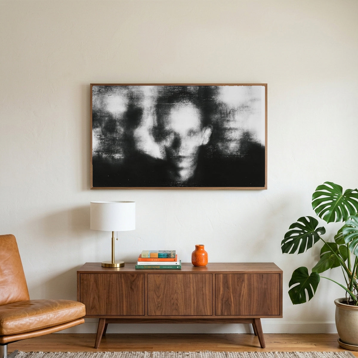Blurred faces art on a TV above a walnut credenza with a brass lamp and a monstera plant