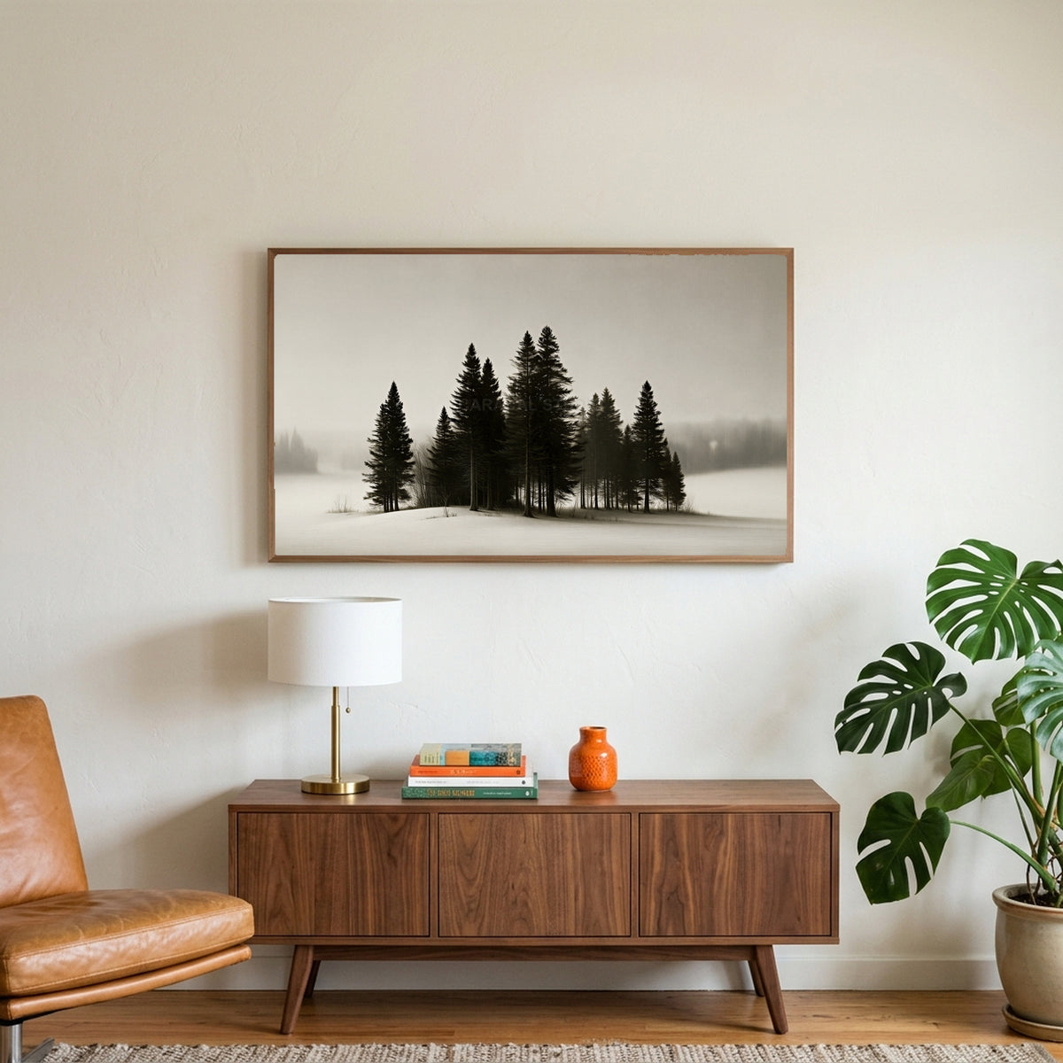 Snowy pine trees art on a TV above a walnut credenza with a brass lamp and a monstera plant