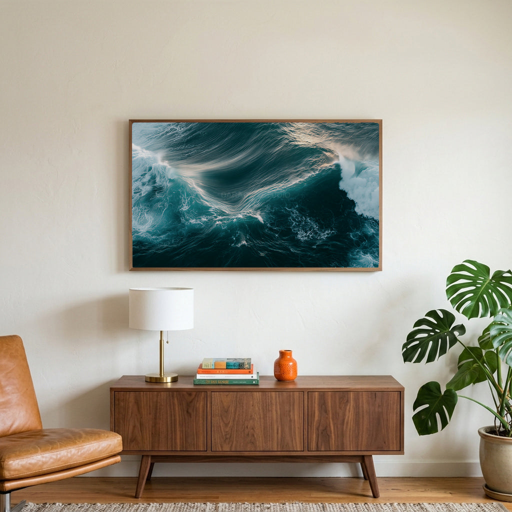 Aerial ocean waves art on a TV above a walnut credenza with a brass lamp and a monstera plant