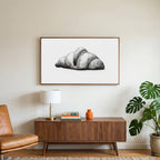 Croissant etching art on a TV above a walnut credenza with a brass lamp and a monstera plant