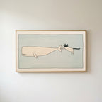 Frame TV art of a cat riding a flying whale in a light wood frame on a warm white wall